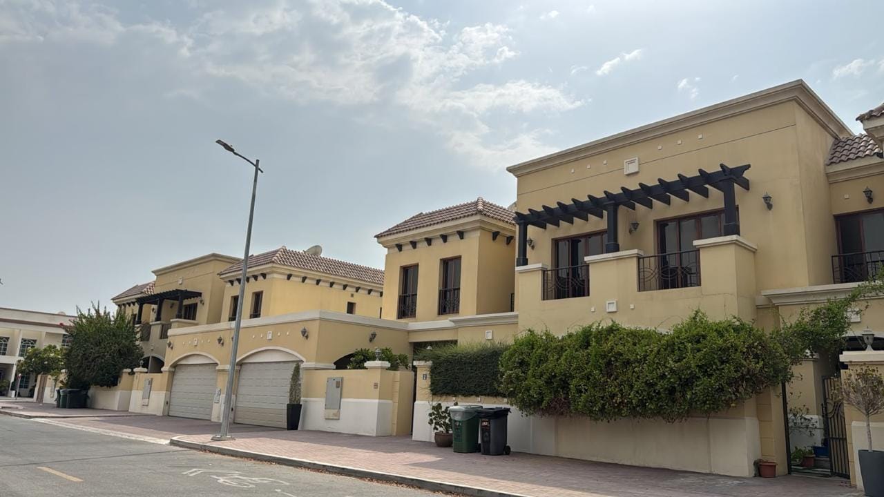 Street of Mediterranean-style villas with terracotta roofs, timber pergolas and arched double garages in Jumeirah, Dubai