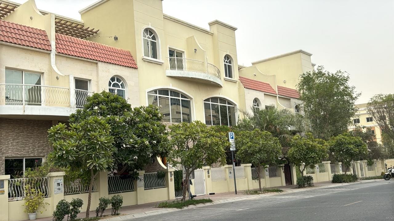 Cream townhouse facade with curved balcony and stone cladding in JVC, Dubai