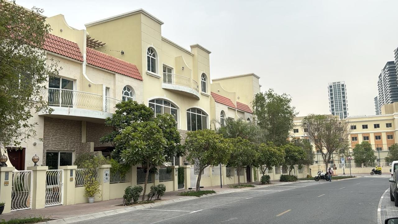 Townhouse row with red tile roofs and arched windows in Jumeirah Village Circle, Dubai