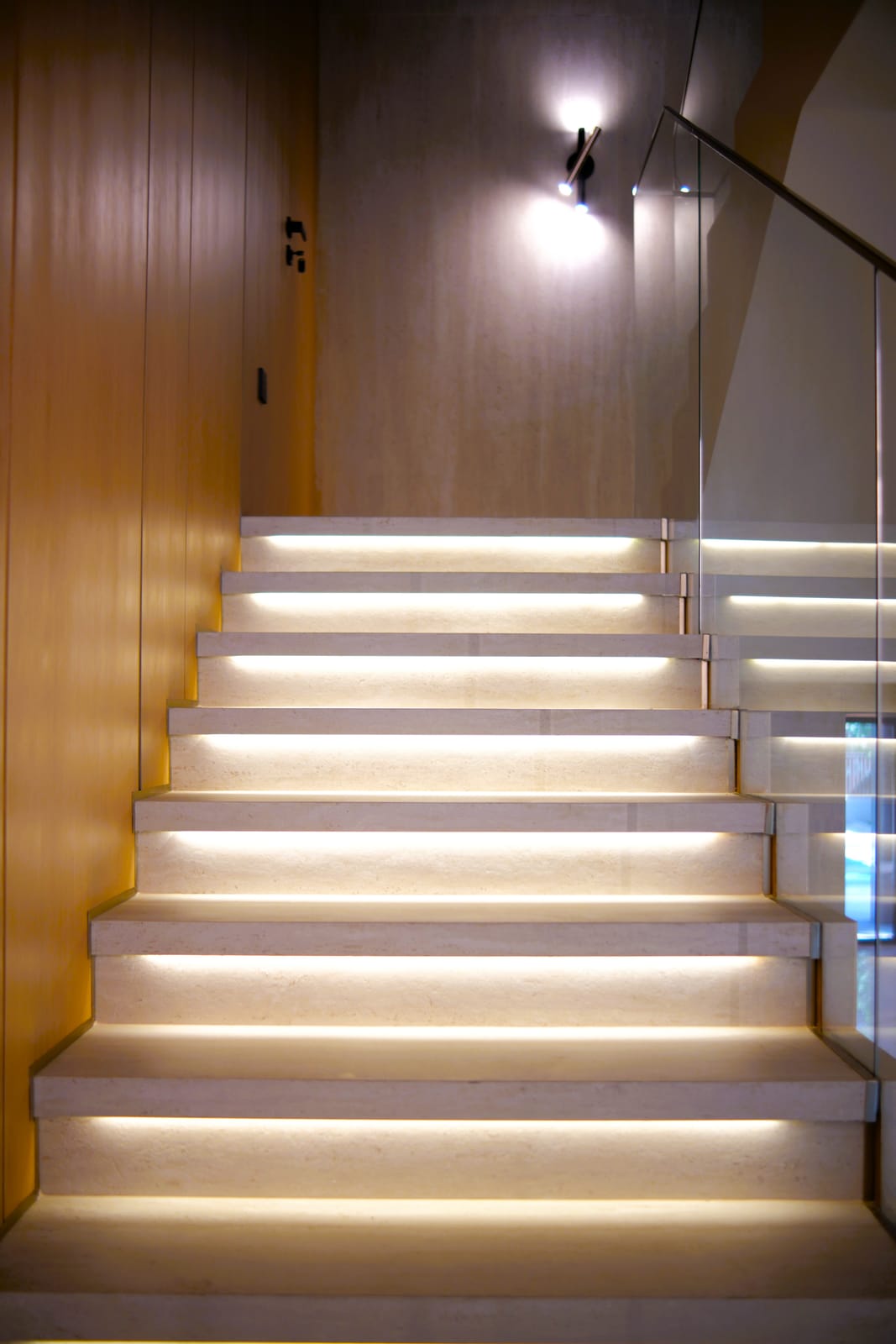 Feature staircase with LED-lit stone treads and timber-panelled walls