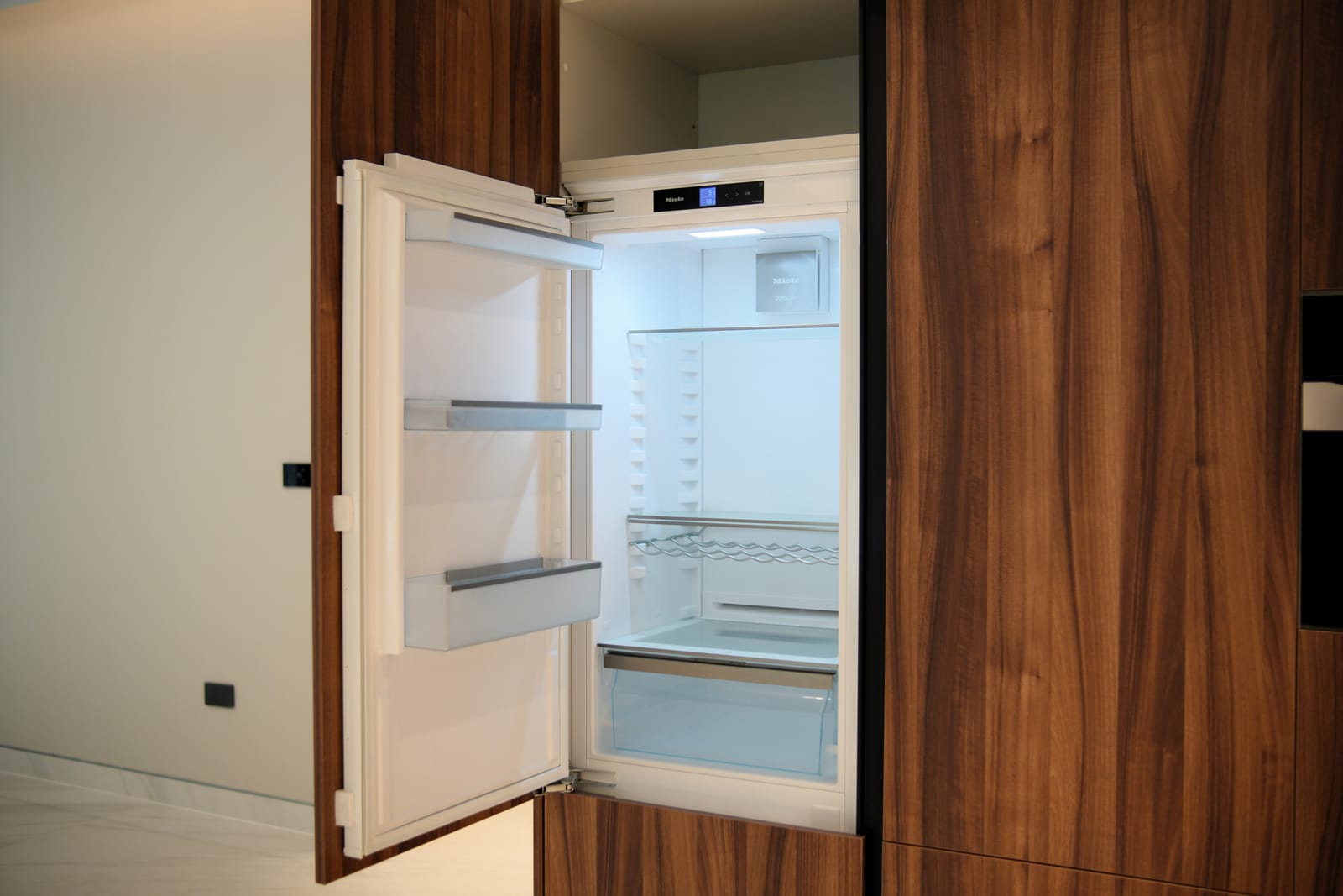 Integrated refrigerator concealed behind walnut kitchen joinery in a Meydan villa