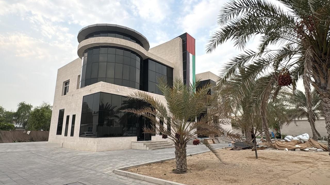 Modern villa with curved glass curtain wall and beige stone cladding in Nad Al Sheba, Dubai